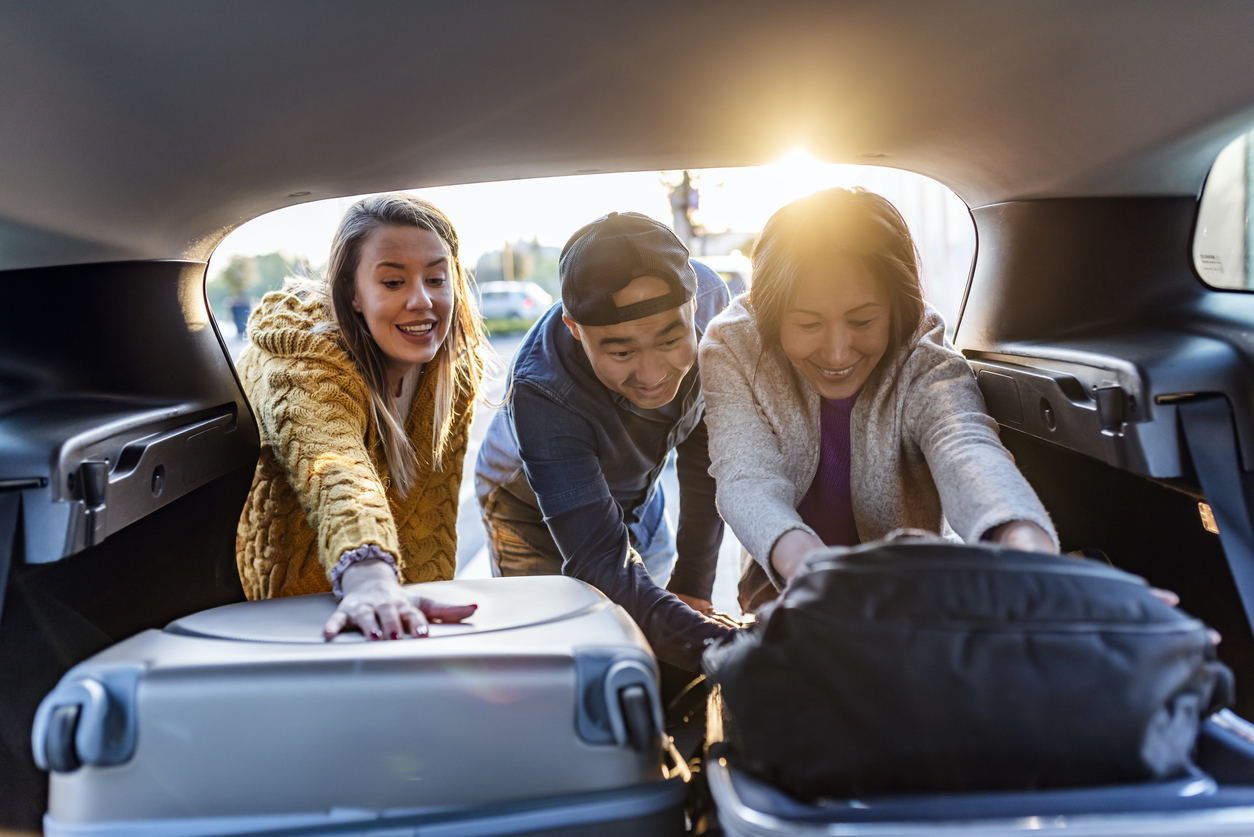 Three people getting luggage out of car