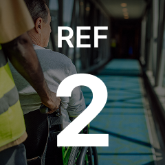 Person pushing someone in a wheelchair down a corridor. The overlay text reads, "REF 2."
