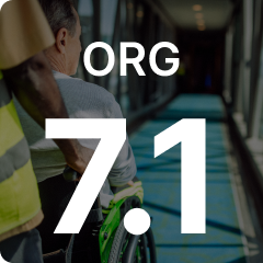 Person in a wheelchair being assisted through a corridor, with large text overlay "ORG 7.1".