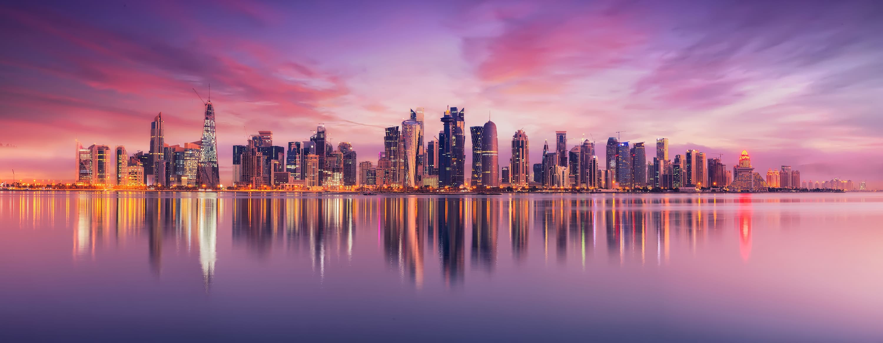 view of boats sat in the water overlooking city at sunset