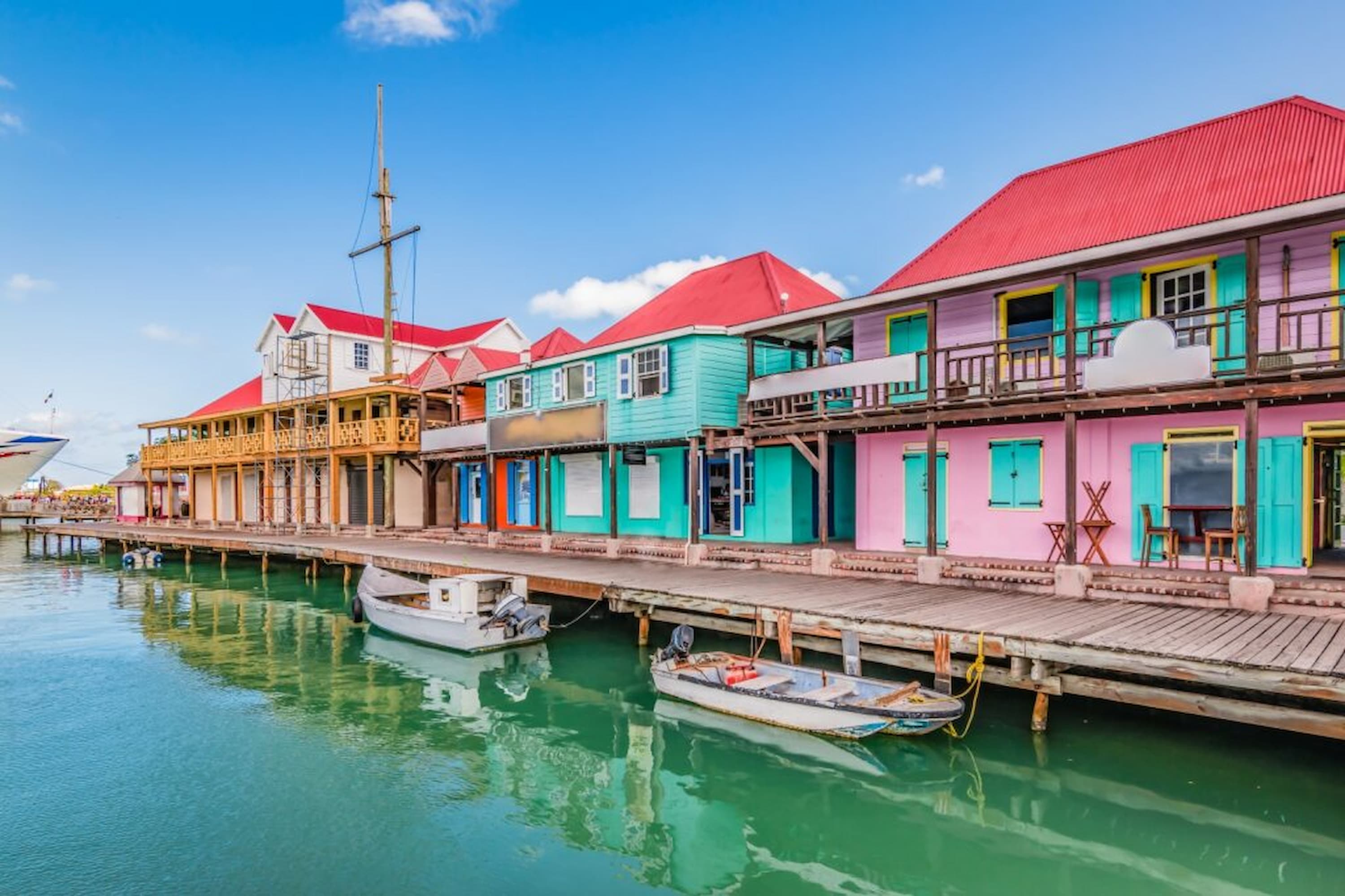 Colourful waterfront buildings with red roofs line a wooden dock