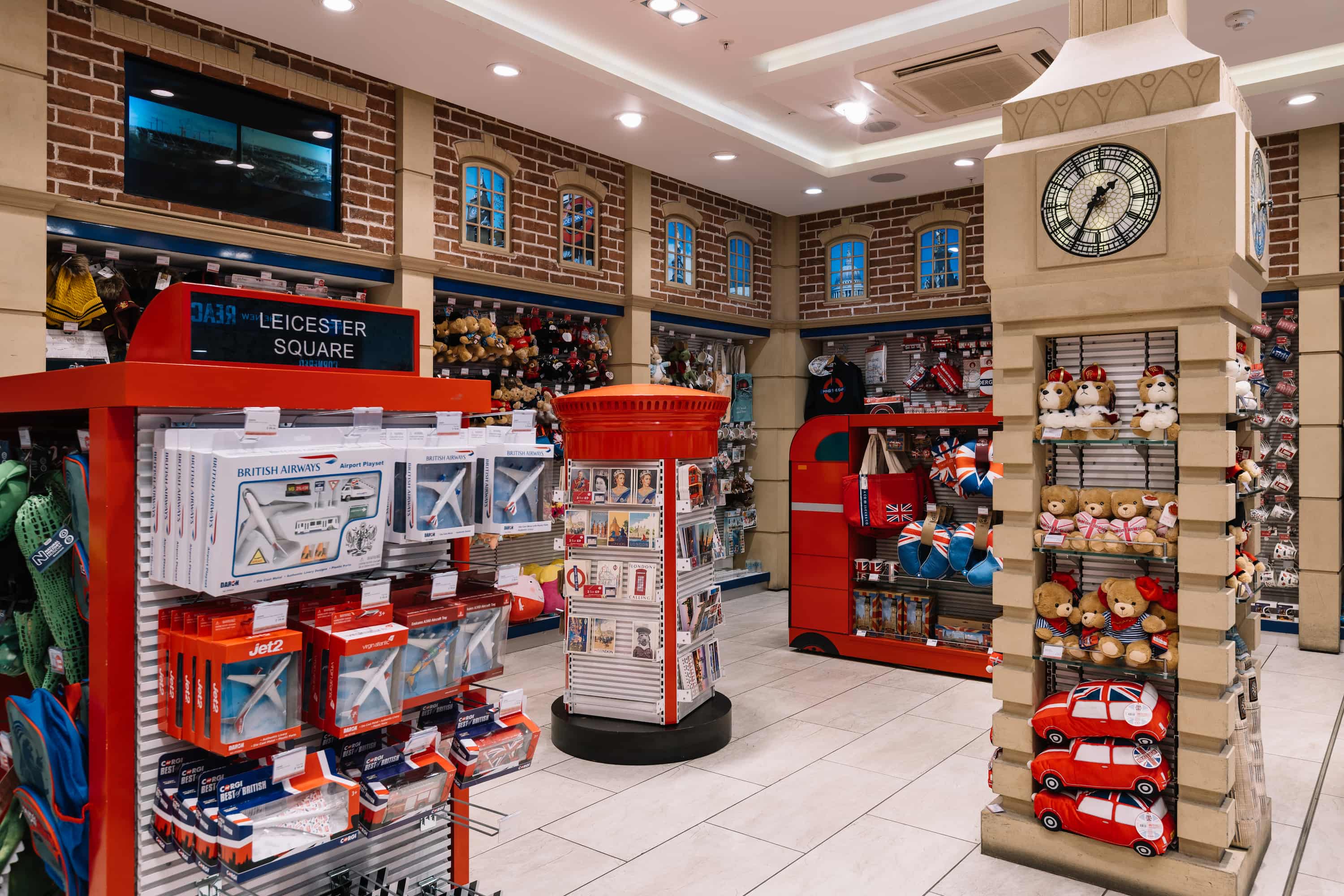 Toy store with London-themed décor, featuring red accents, teddy bears, toy planes, buses, and a clock tower display.