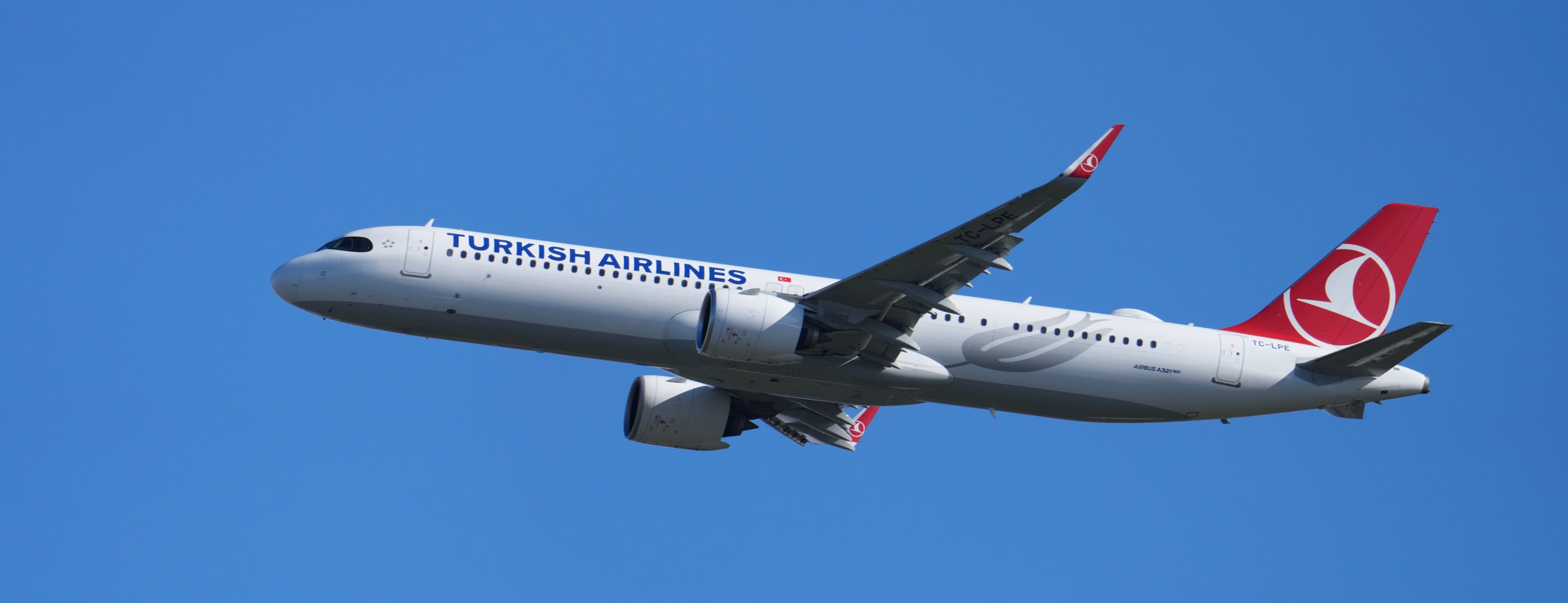 Turkish Airlines passenger plane flying in a clear blue sky.