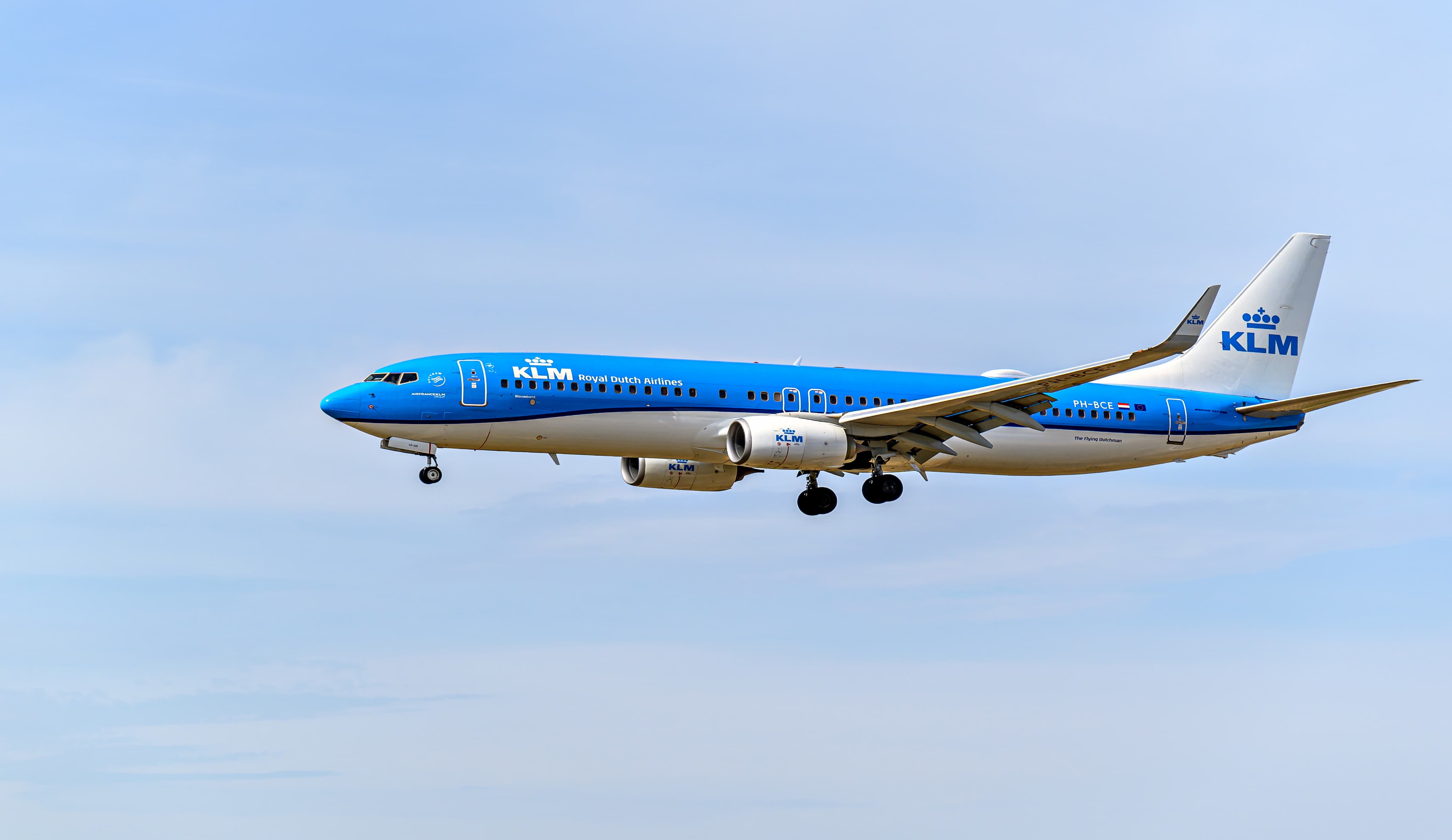 A KLM Royal Dutch Airlines plane in flight against a clear blue sky.
