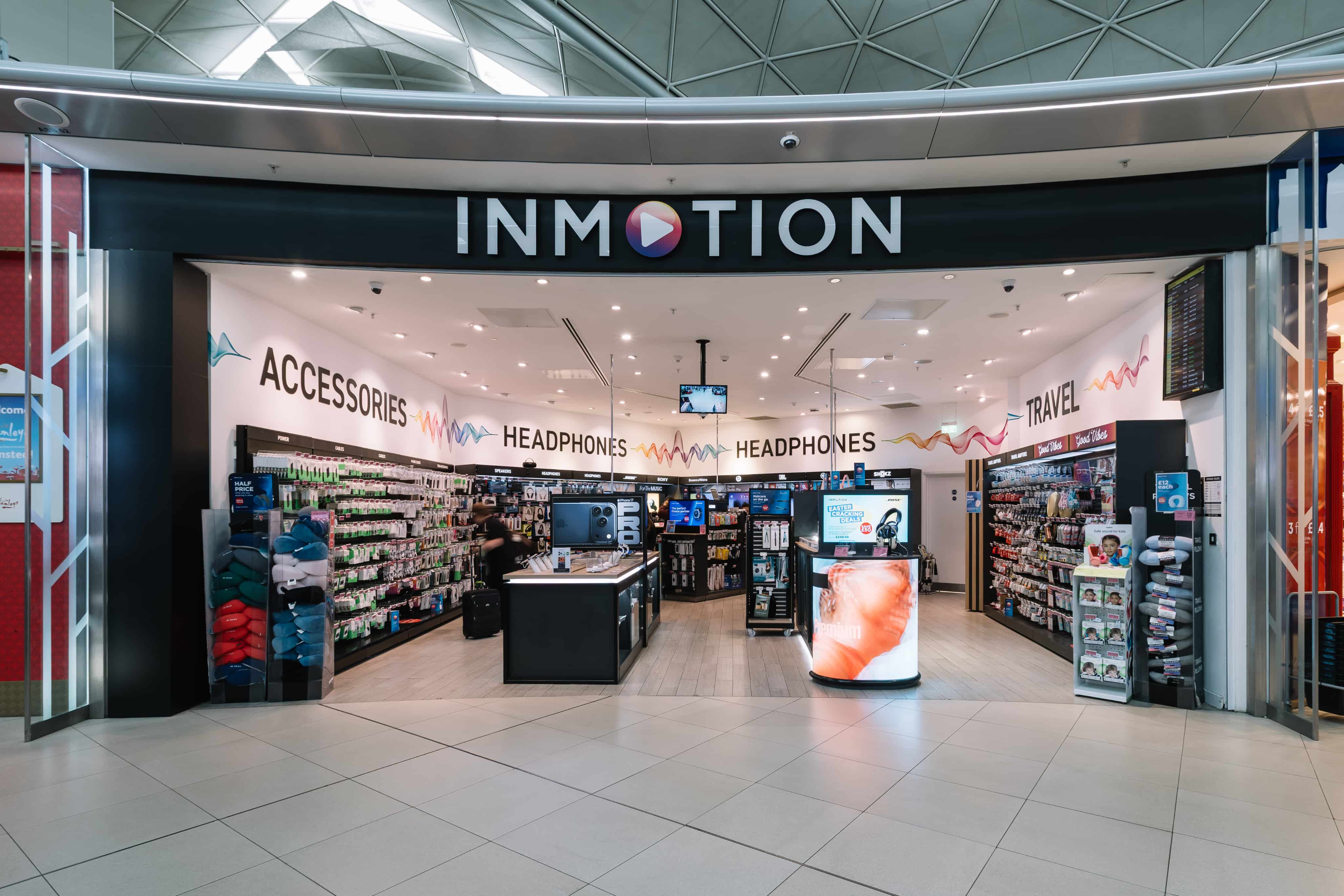 Storefront of INMOTION featuring accessories, headphones, and travel items, displayed with bright lighting and organised shelves.
