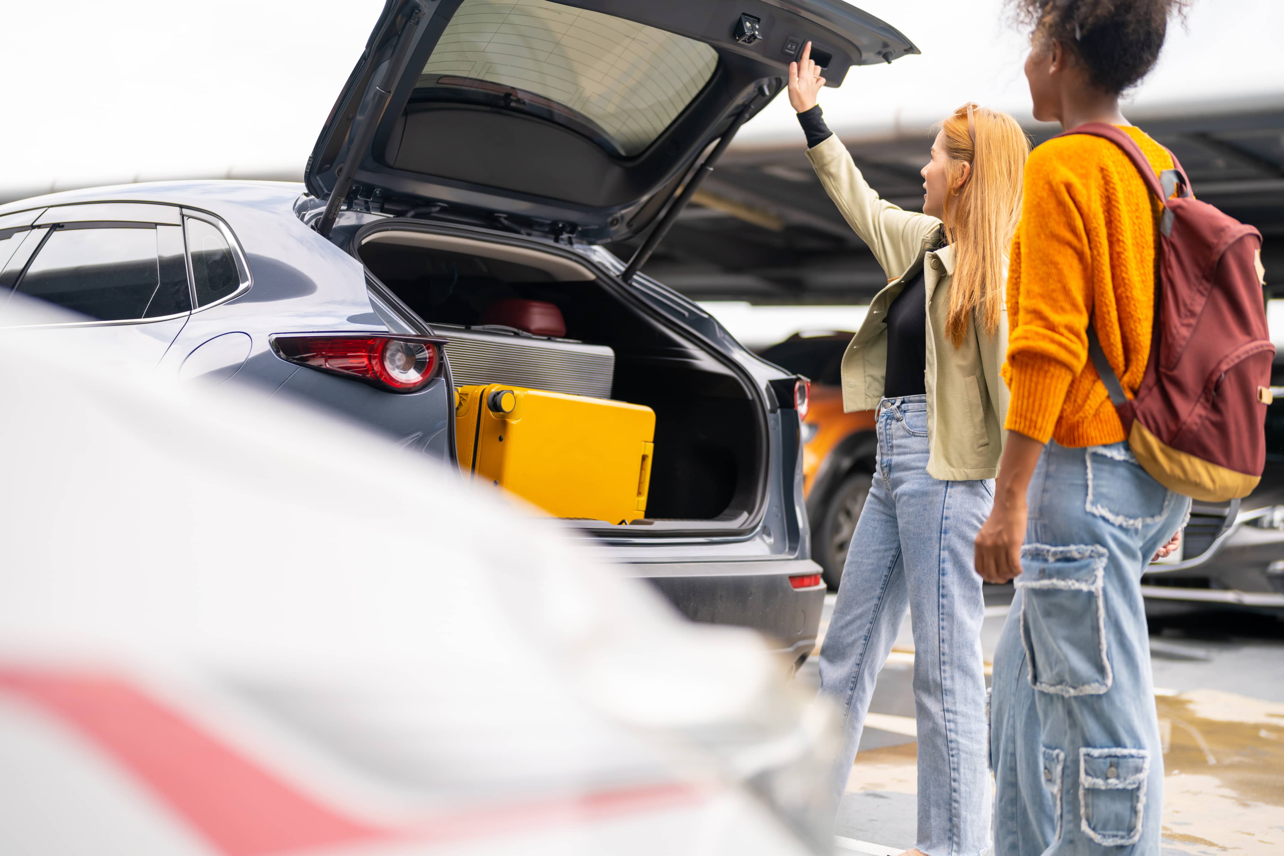 Two women closing car boot
