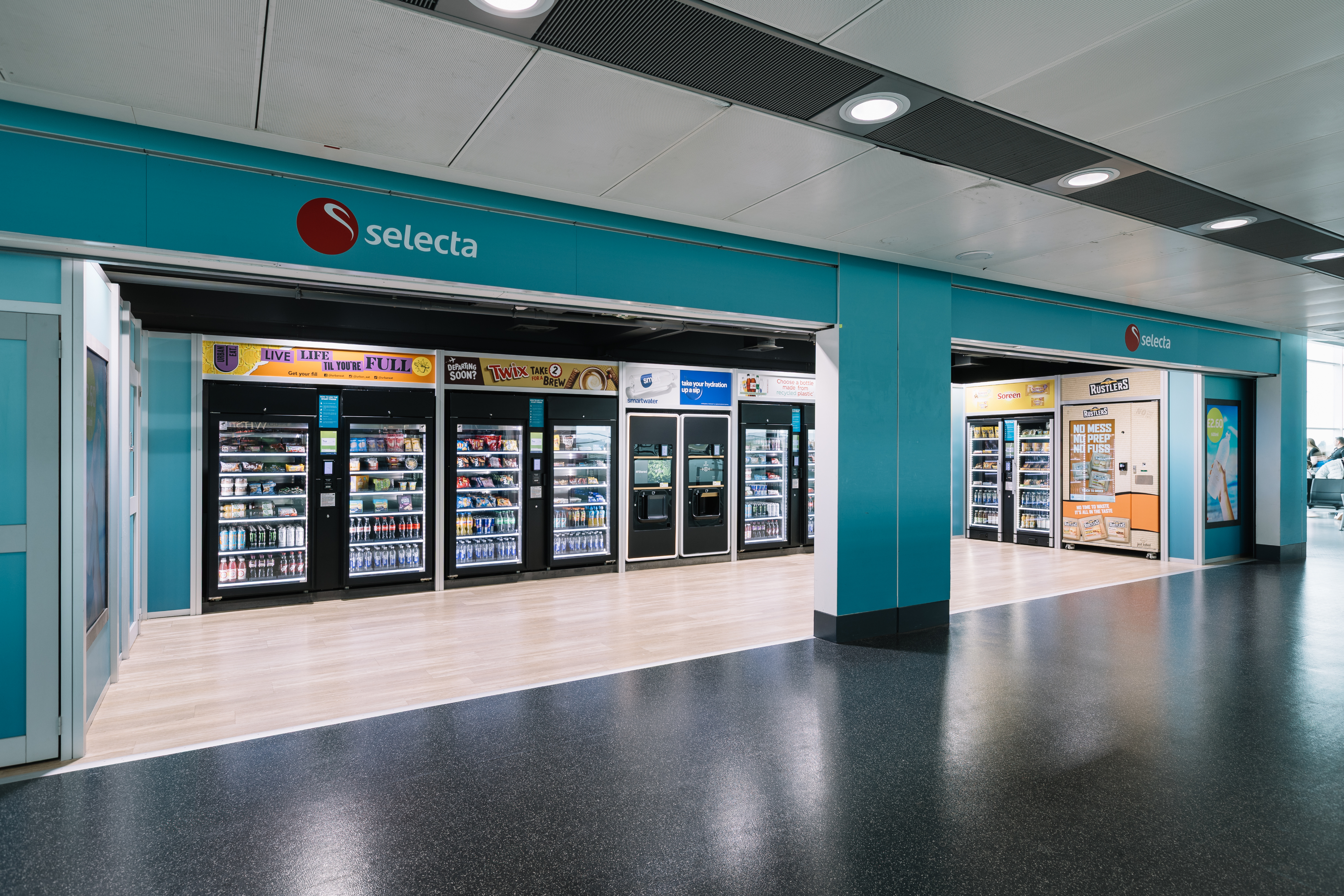 A Selecta vending area with various snack and drink machines in a brightly lit, open space.