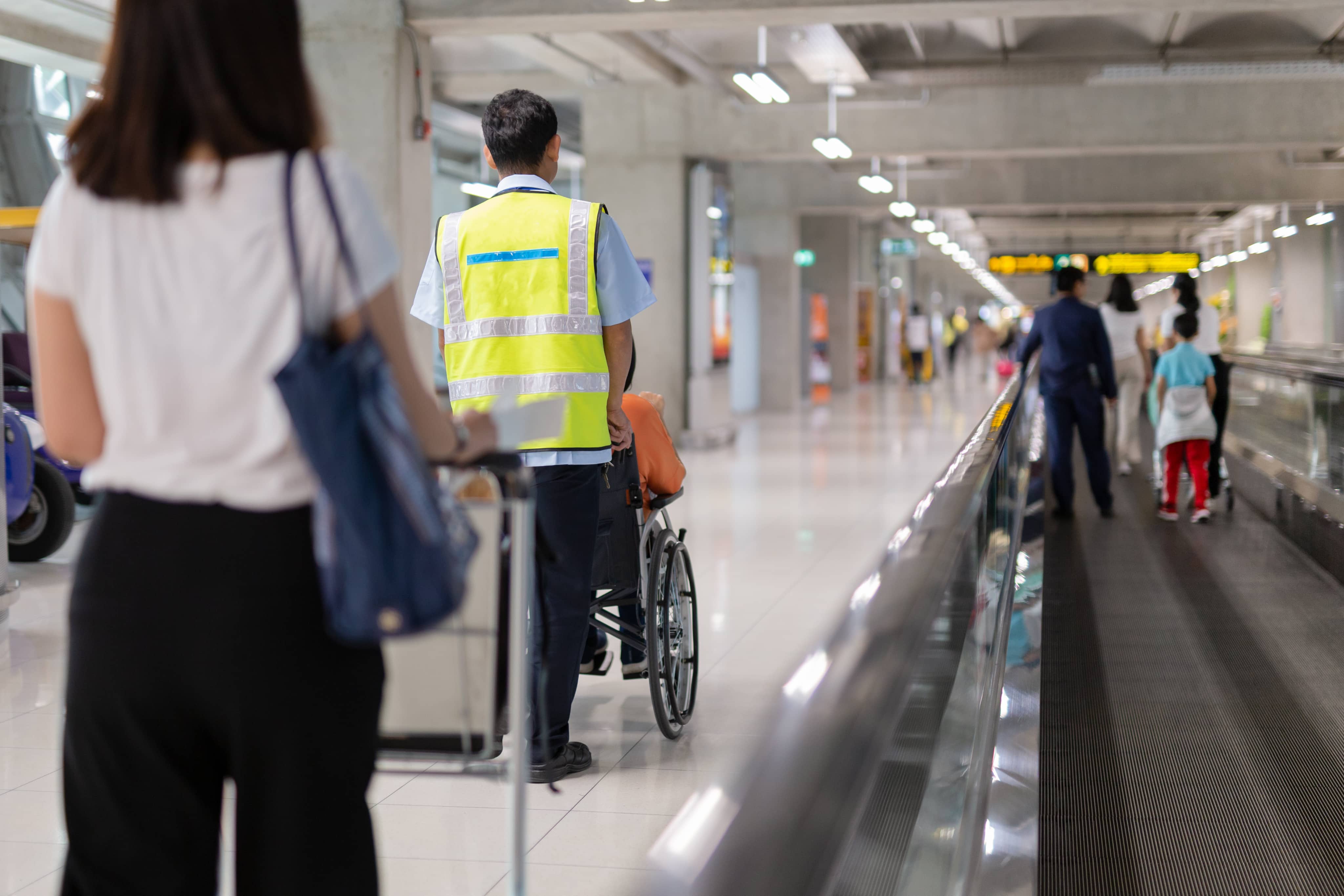 Assisted Travel team member pushing passenger in wheelchair through airport