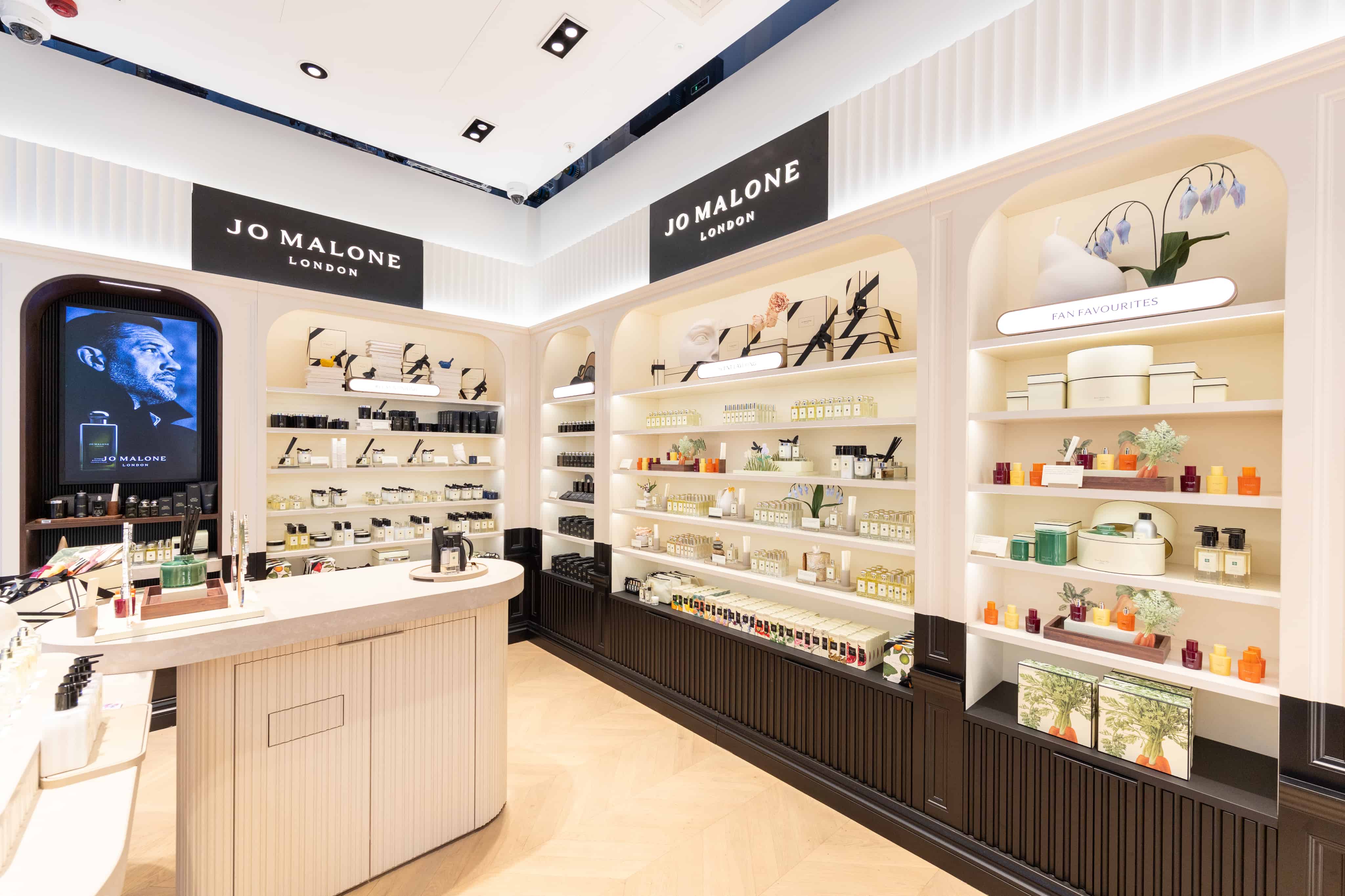 Luxury fragrance store with neatly arranged shelves of perfumes and products, featuring branded signage and elegant decor.