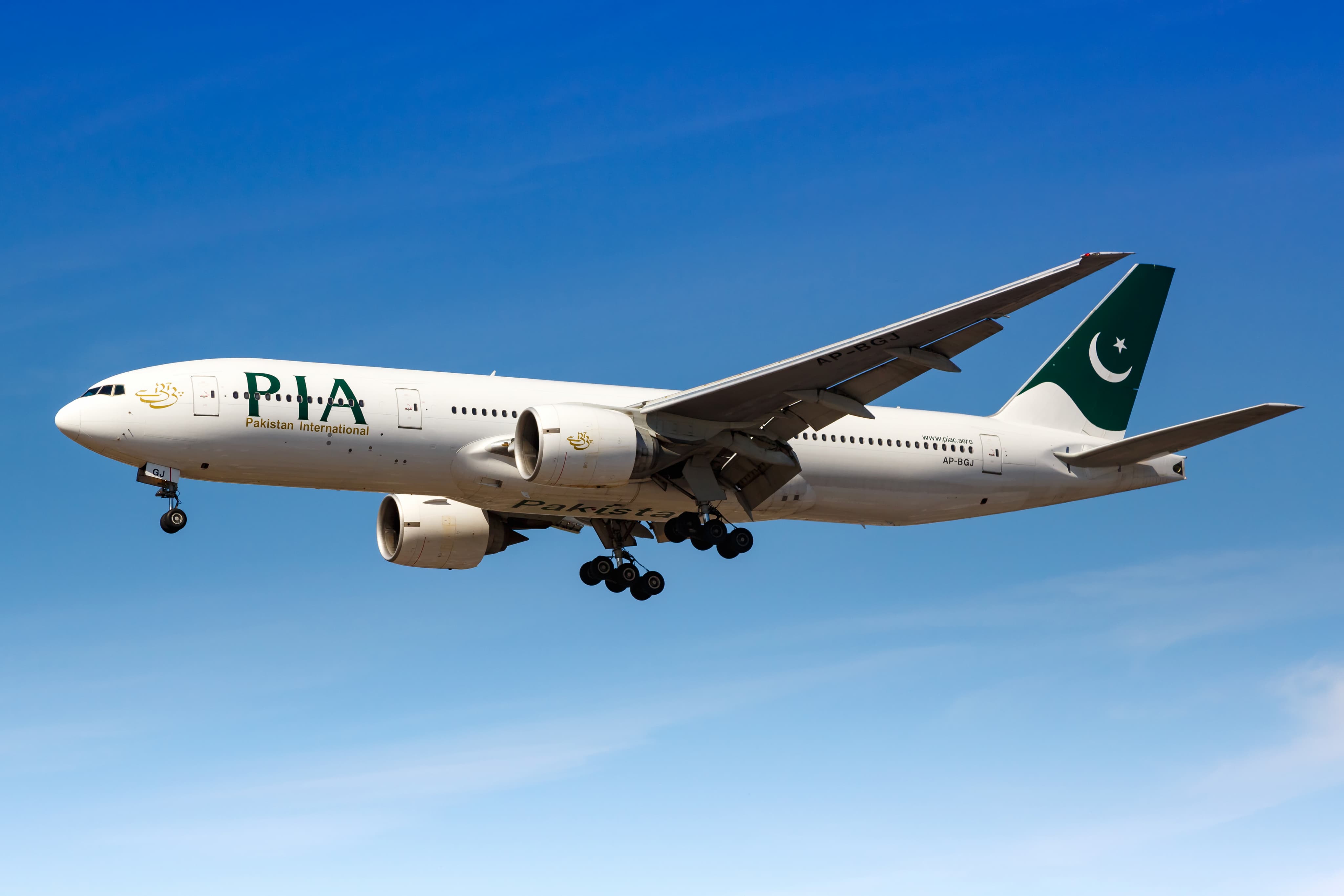 A PIA passenger airplane with landing gear extended flying against a clear blue sky.