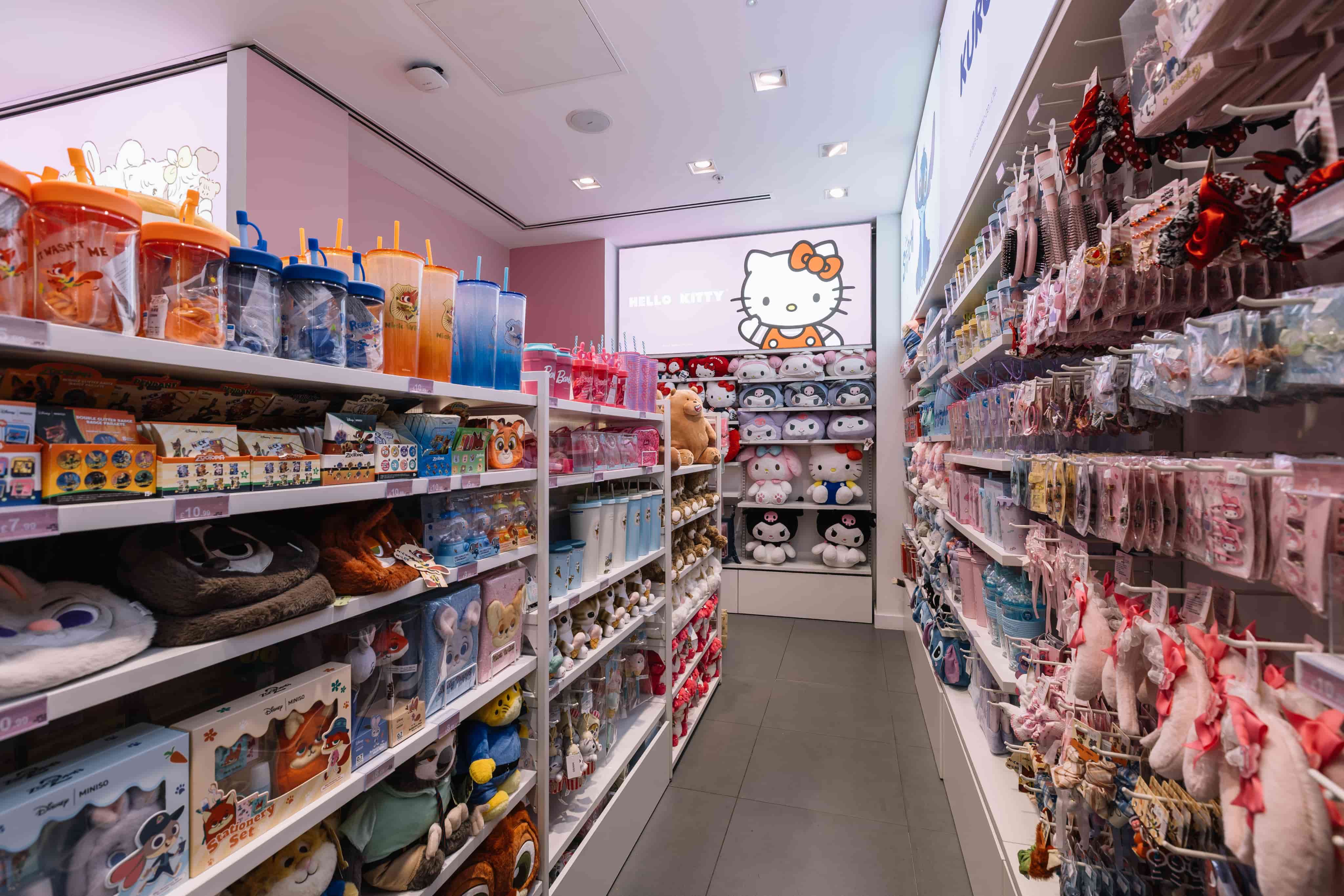 Toy store aisle with colourful stuffed animals, drink bottles, and accessories, featuring a prominent Hello Kitty display on the back wall.