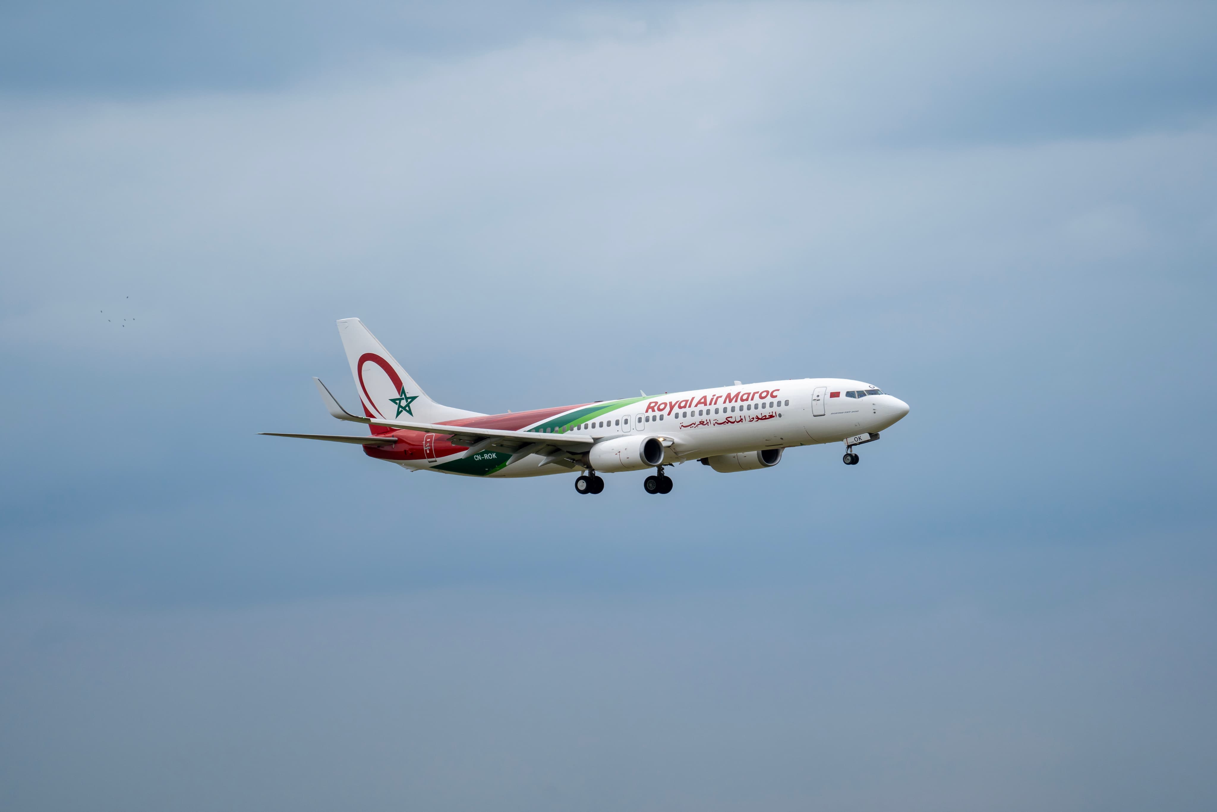 A Royal Air Maroc passenger airplane flying in a cloudy sky.