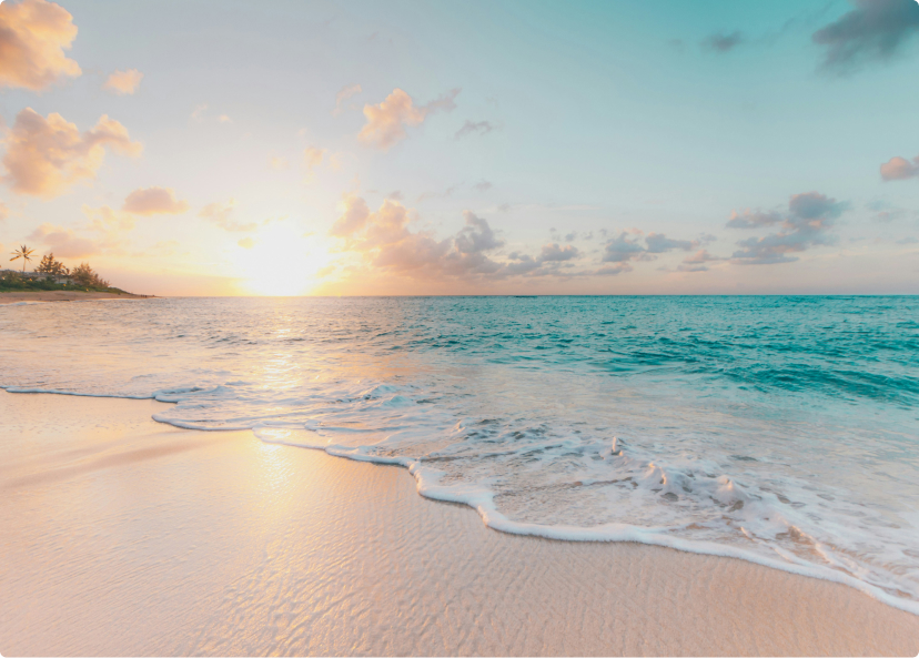 Sunset over a serene beach with gentle waves meeting the sandy shore, under a sky painted in pastel hues.